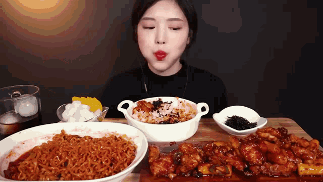 a woman is eating a variety of foods including noodles and chicken