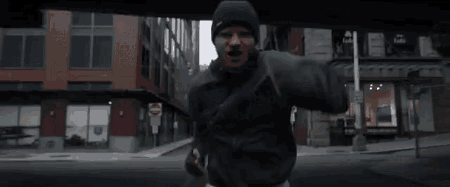 a man wearing a black hat is running down a city street