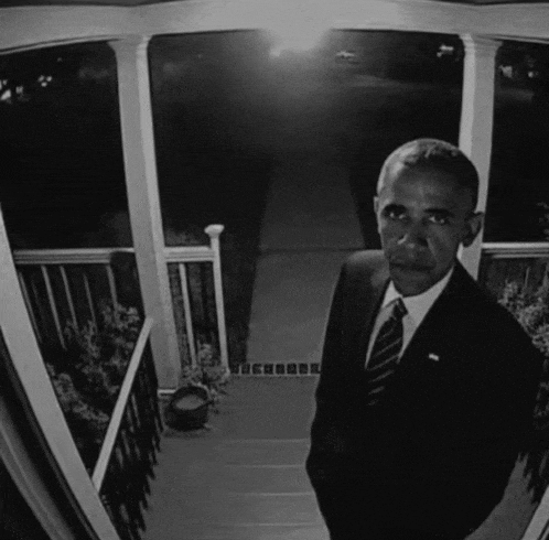 a man in a suit and tie is standing in front of a porch