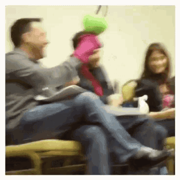 a group of people are sitting in chairs and one man is holding a green ball in his hand