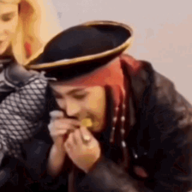 a person wearing a pirate hat is eating a piece of food
