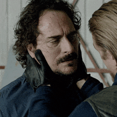 a man with a beard and mustache is being held by another man