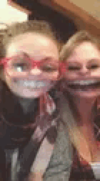 two women wearing red glasses and scarves are posing for a picture together .