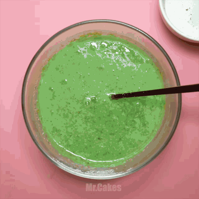 a bowl of green liquid with a spoon in it and the words mr.cakes below it