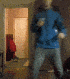 a man in a blue jacket is dancing in front of a door