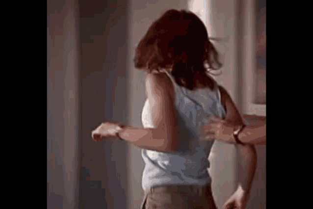 a woman in a tank top is dancing with a man .