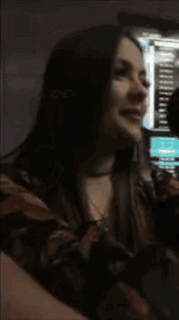 a close up of a woman 's face with a phone in the background