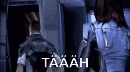 a man and a woman are standing next to each other in a room with the word taaah written on the bottom .