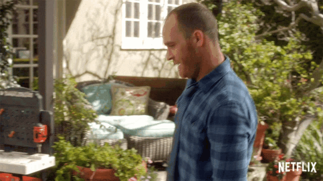 a man in a blue plaid shirt is standing in front of a netflix ad