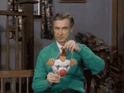 a man in a green sweater is sitting in a chair holding a clown toy .