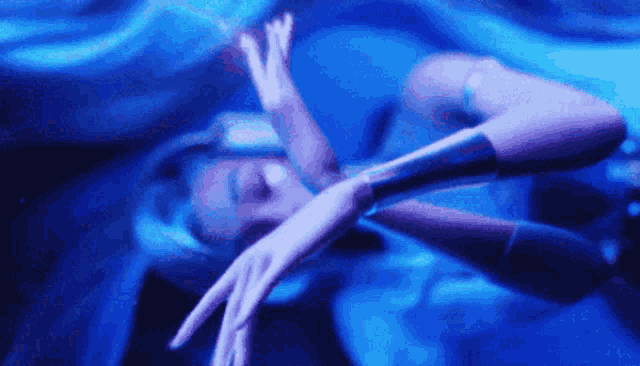 a woman is laying in the water with her arms outstretched in a dark room .
