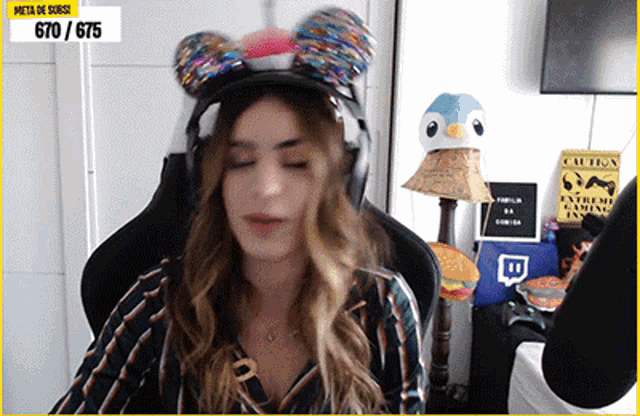 a woman wearing a mickey mouse hat is sitting in a chair with her eyes closed