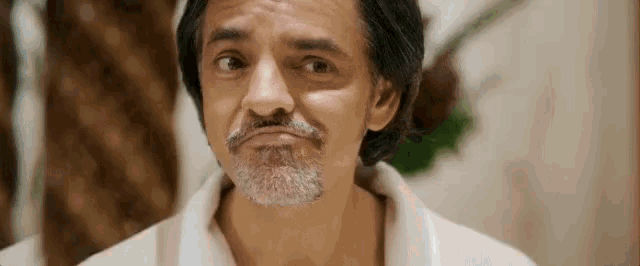 a man with a beard is making a funny face while wearing a white robe .