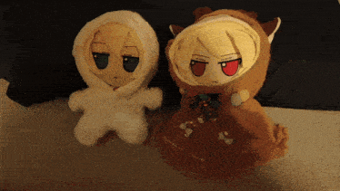 two stuffed animals are sitting next to each other with one wearing a white outfit