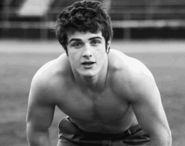 a black and white photo of a shirtless man with a belt that says ' nyc ' on it