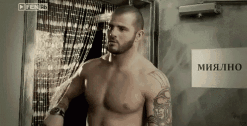 a shirtless man is standing in front of a door with a sign that says миально on it
