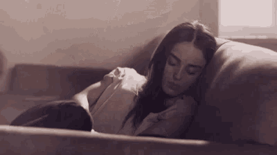 a woman is sleeping on a couch with a pillow on her chest .