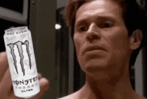 a man is holding a can of monster energy drink in his hand