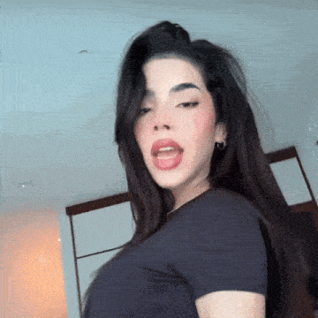 a woman with long dark hair is wearing a black shirt and earrings .