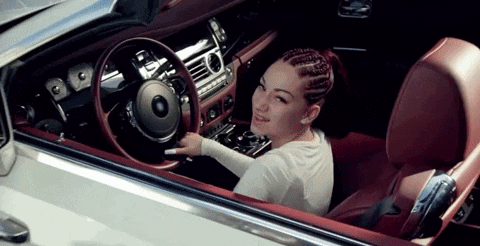 a woman is sitting in the driver 's seat of a white convertible car