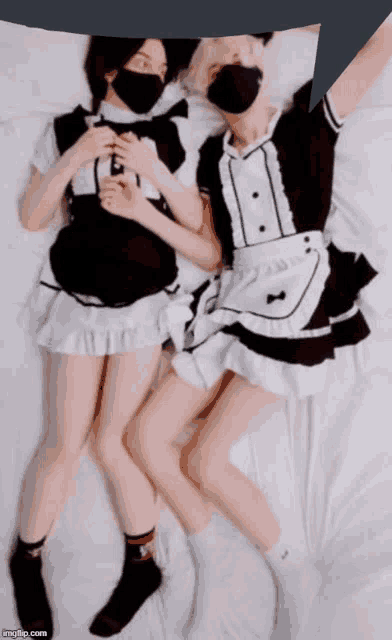 two maids are laying on a bed with a speech bubble in the background
