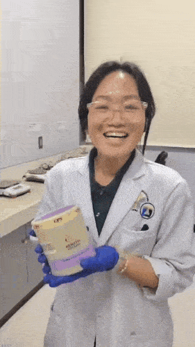 a woman in a lab coat is smiling while holding a container that says cps on it