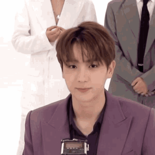 a young man in a purple suit is holding a recorder