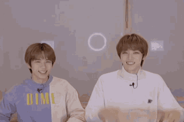 two young men are standing next to each other and one has a microphone on his neck