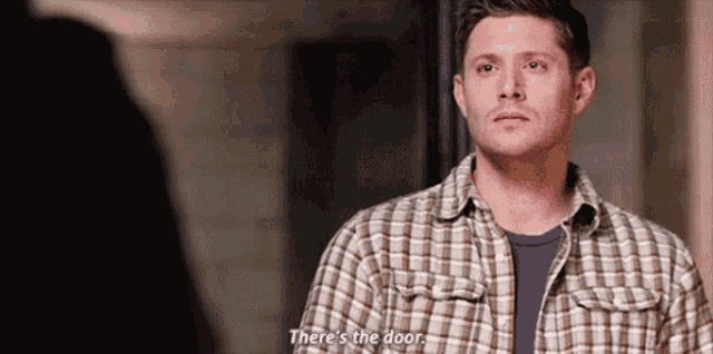 a man in a plaid shirt is talking to another man .