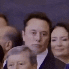 a man in a suit is standing in a crowd of people and looking at the camera .