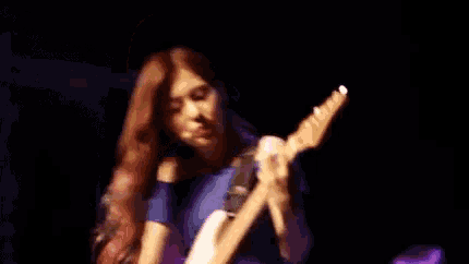 a woman is playing an electric guitar on stage .