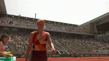 a woman is standing on a tennis court in front of a stadium .