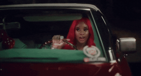 a woman with red hair is sitting in a green car covering her mouth .