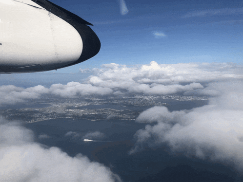 a view of a city from an airplane window with a blue sky and clouds