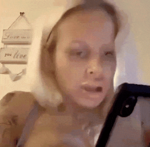 a woman is taking a picture of herself with a sign that says love you live in the background