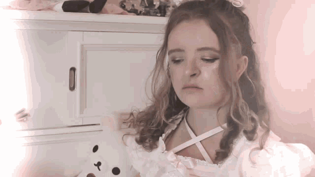 a woman in a pink dress holds a stuffed animal
