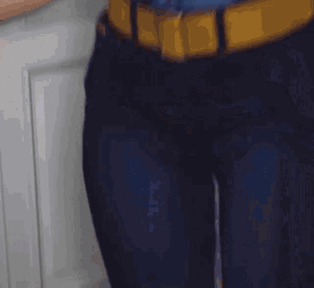 a woman in a blue shirt and black pants is standing in front of a door