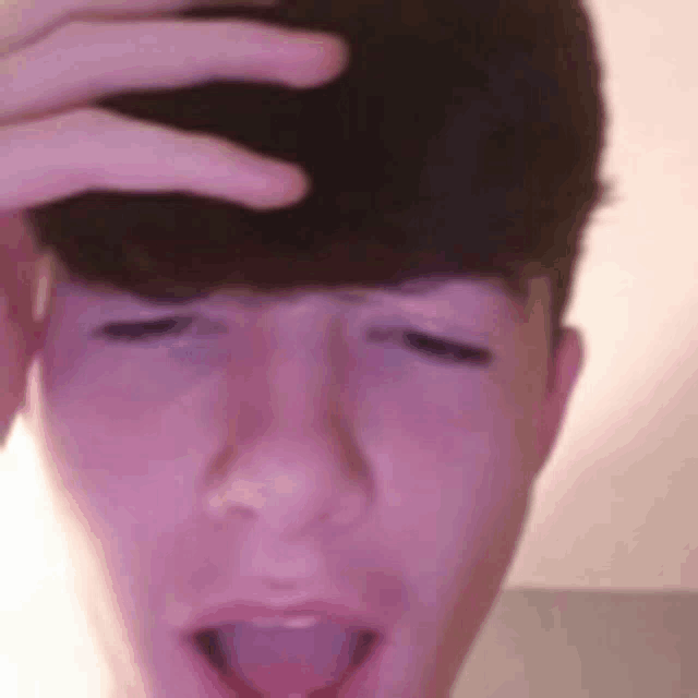 a close up of a person 's face with their hand on their forehead .