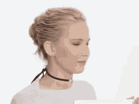 a woman wearing a choker and a white sweater is looking down .