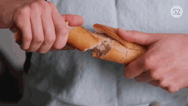 a person is holding a loaf of bread with the number 52 on the bottom right