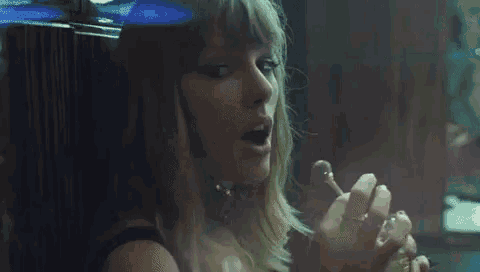a woman is smoking a cigarette in a dark room while looking out a window .
