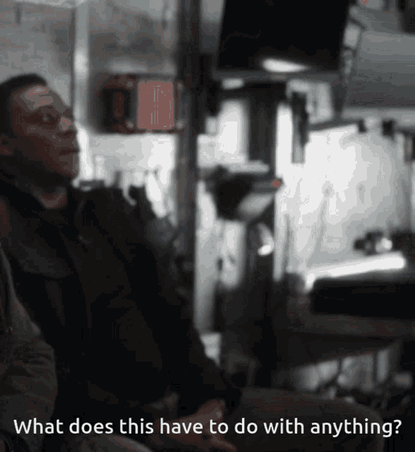 a man sits in a dark room with the words what does this have to do with anything