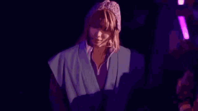 a woman wearing a knitted hat and a purple shirt is pointing at something