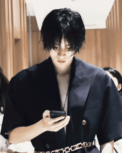 a man in a black jacket looks at his phone