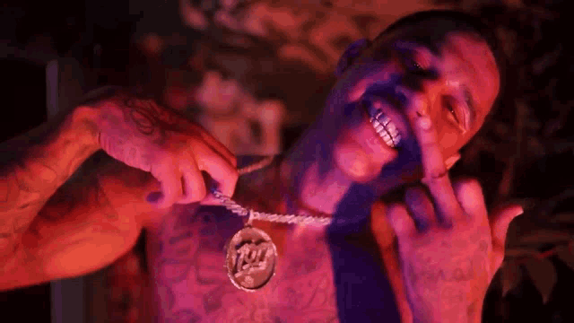 a shirtless man is wearing a necklace with a pendant that says t & l on it
