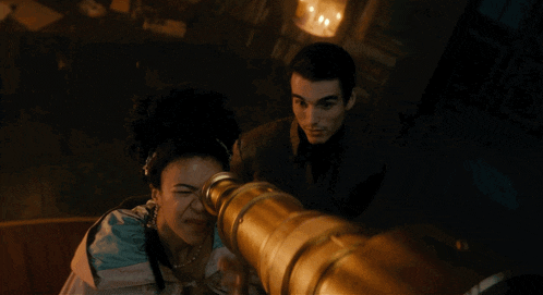 a man and a woman looking through a telescope in a dark room