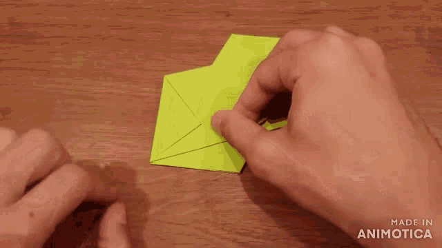 a person is holding a piece of yellow paper with the words made in animotica visible