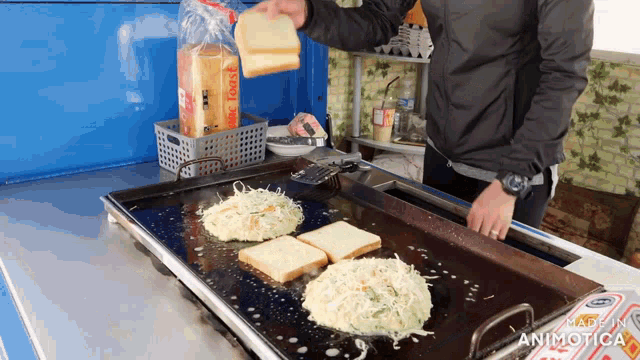 a man is cooking sandwiches on a grill with a bag of magic toast behind him