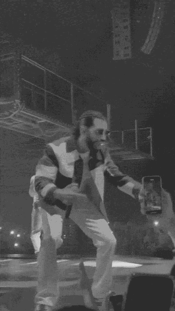 a black and white photo of a man on a stage surrounded by fans