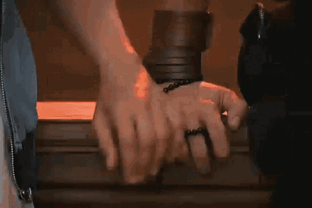 a man and a woman are holding hands in a dark room . the woman has a ring on her finger .